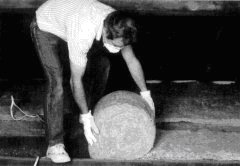 Laying insulation between rafters, wearing a mask.